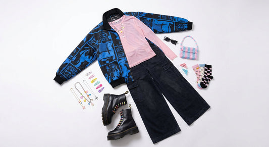 A flatlay of a layered Harajuku street style outfit featuring an oversized jacket, wide-leg pants, platform boots, and a colorful collection of accessories arranged on a white surface.