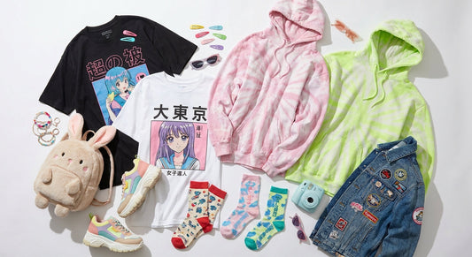 A colorful editorial flat lay of Japanese Harajuku streetwear clothing and accessories including graphic tees, kawaii accessories, and chunky sneakers arranged on a white surface.