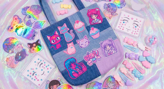 A flat lay of colorful Harajuku accessories including holographic stickers, face gems, kawaii hair clips, and a sticker-covered denim bag arranged on a pastel iridescent surface.