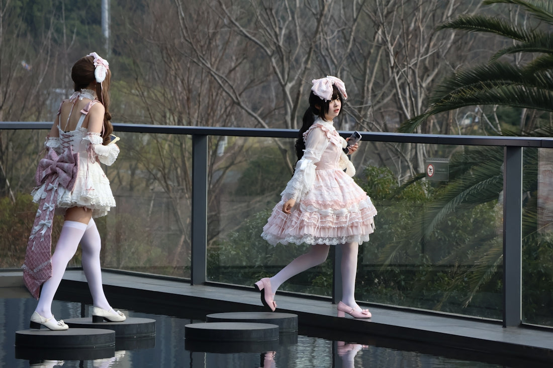 Two women in lolita fashion walk on a walkway.