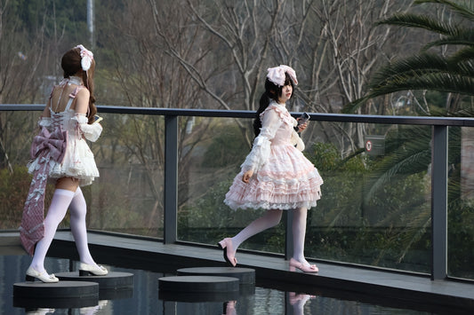 Two women in lolita fashion walk on a walkway.