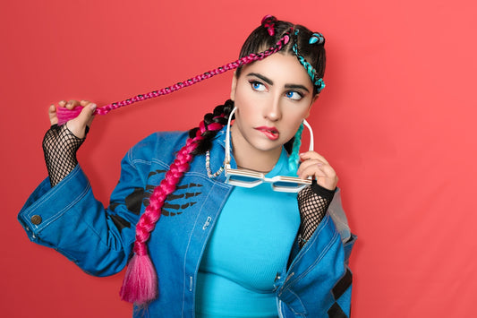 Stylish woman with vibrant braided hair and a thoughtful pose.