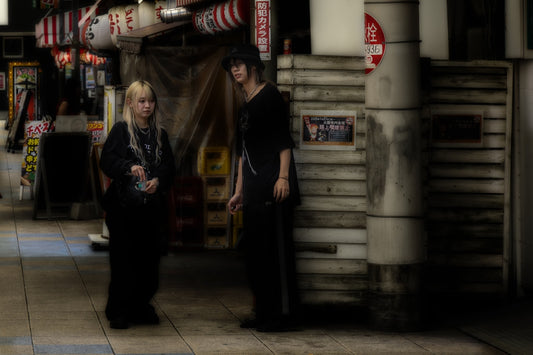 Two people stand on a street at night.