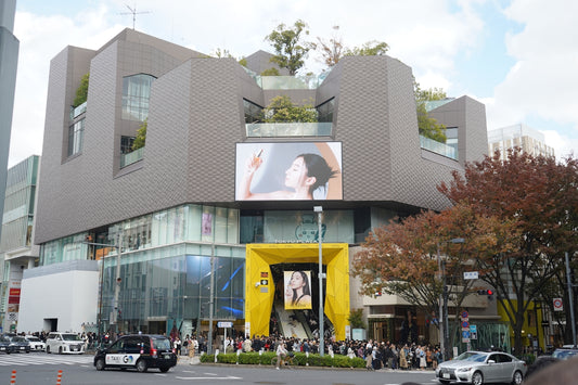 Modern building with rooftop greenery and large advertisements.