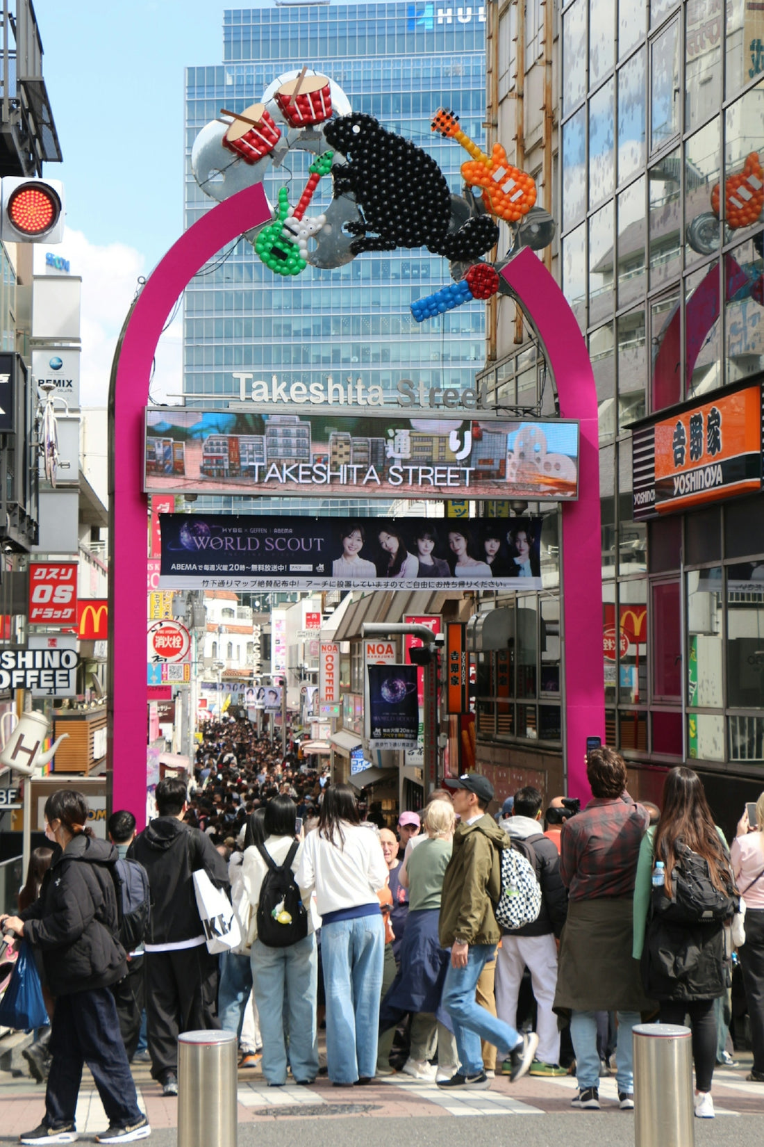 Crowded street under a pink archway with music decorations