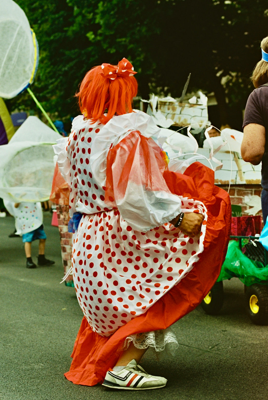 Carnival performer in polka-dot dress and orange wig dancing
