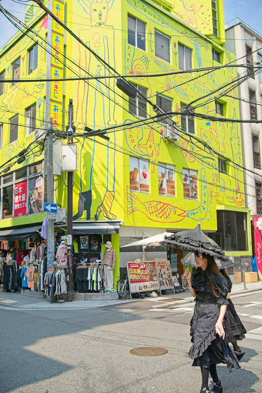 A woman in black walks past a bright yellow building.