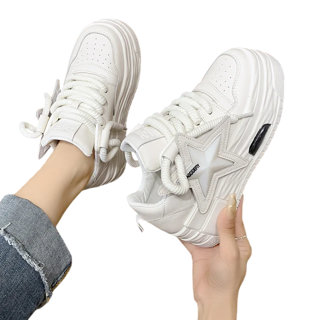Stylish white leather sneakers with star detail and thick laces, perfect for casual outfits.